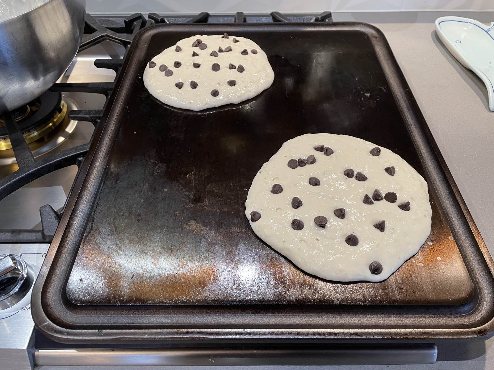 two chocolate chip pancakes on a griddle
